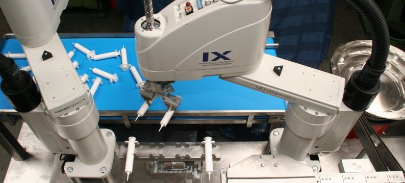 1 Slider IAI Scara Robots pakken injectiepuiten van de band en poistioneren ze om gevuld te worden
